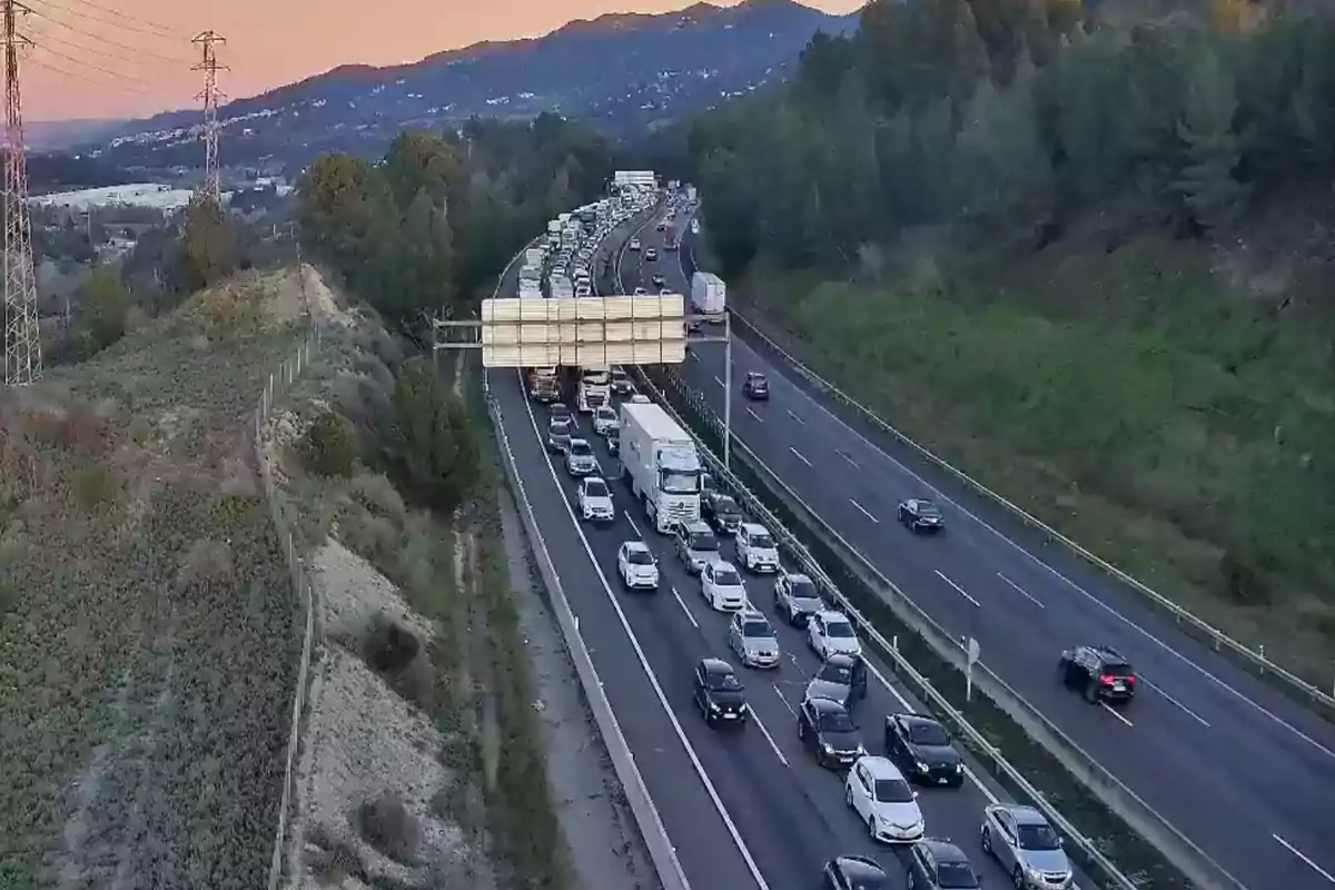 Una carretera con tráfico denso en un entorno montañoso al atardecer.