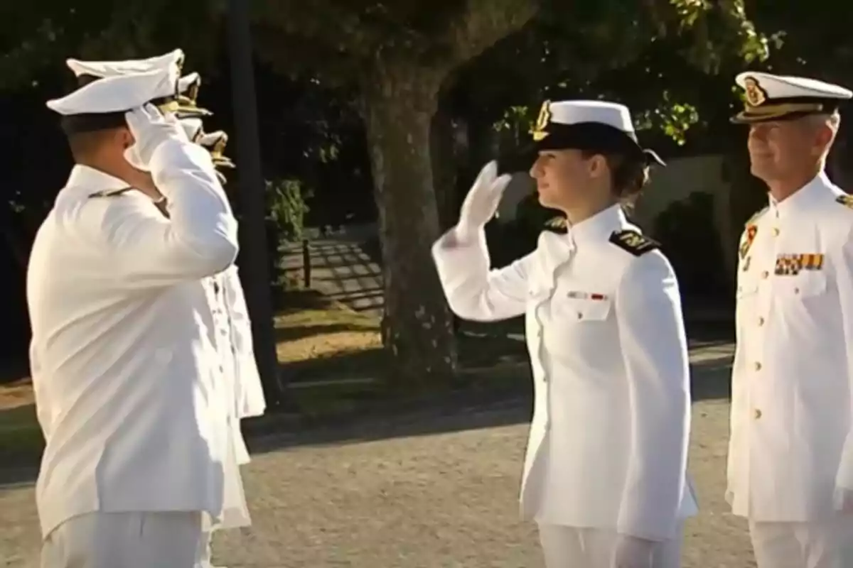 Oficiales de la marina saludándose durante una ceremonia al aire libre.