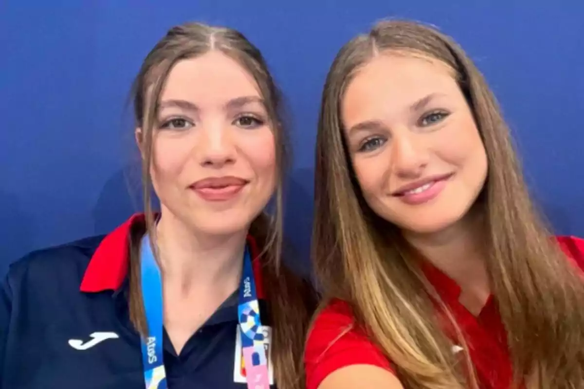 Dos jóvenes sonrientes posando para una selfie con fondo azul. Dos jóvenes sonrientes posando para una selfie con fondo azul.