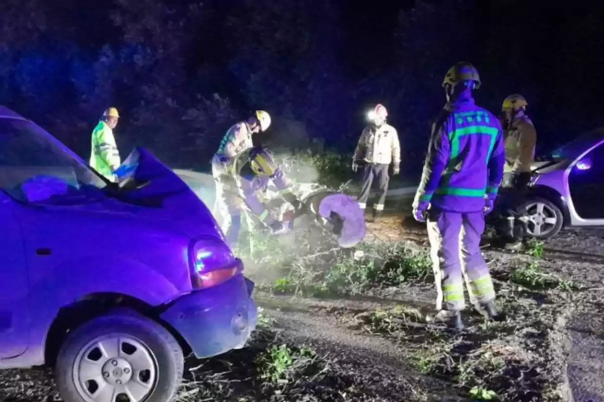 Bombers treballant a l'escena d'un accident automobilístic nocturn.