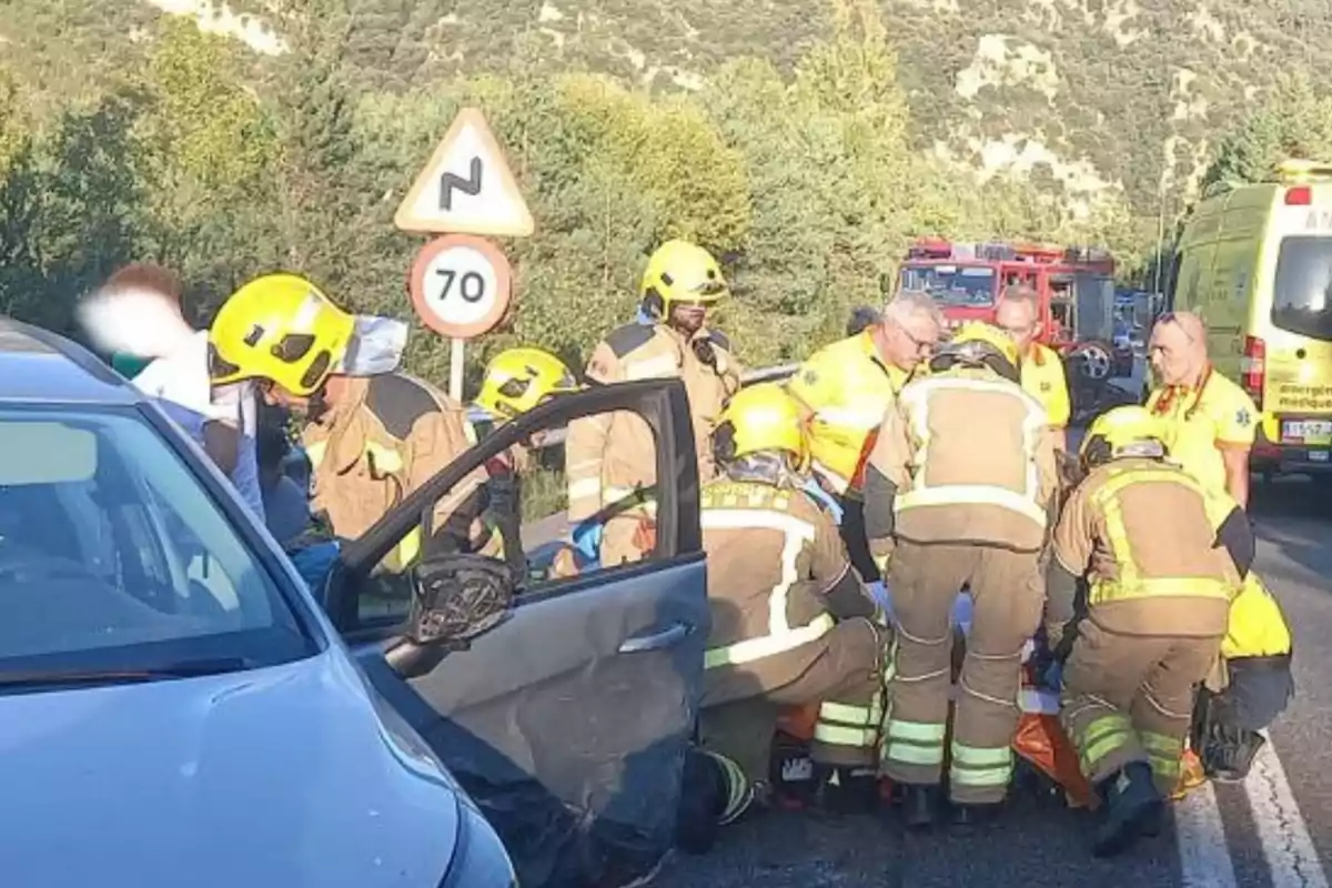 Bombers i personal d'emergència atenen una persona ferida en un accident de trànsit a una carretera.