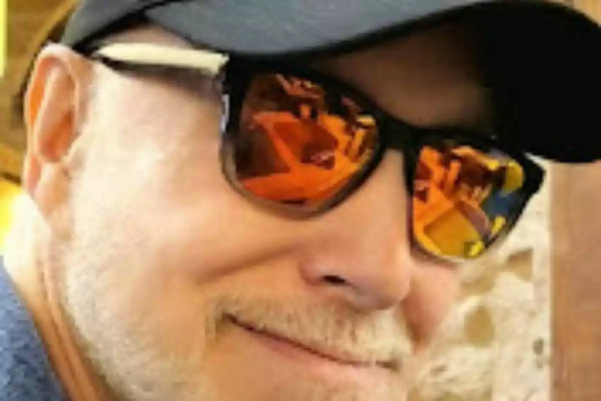 Persona amb gorra negra i ulleres de sol amb reflexes ataronjats.