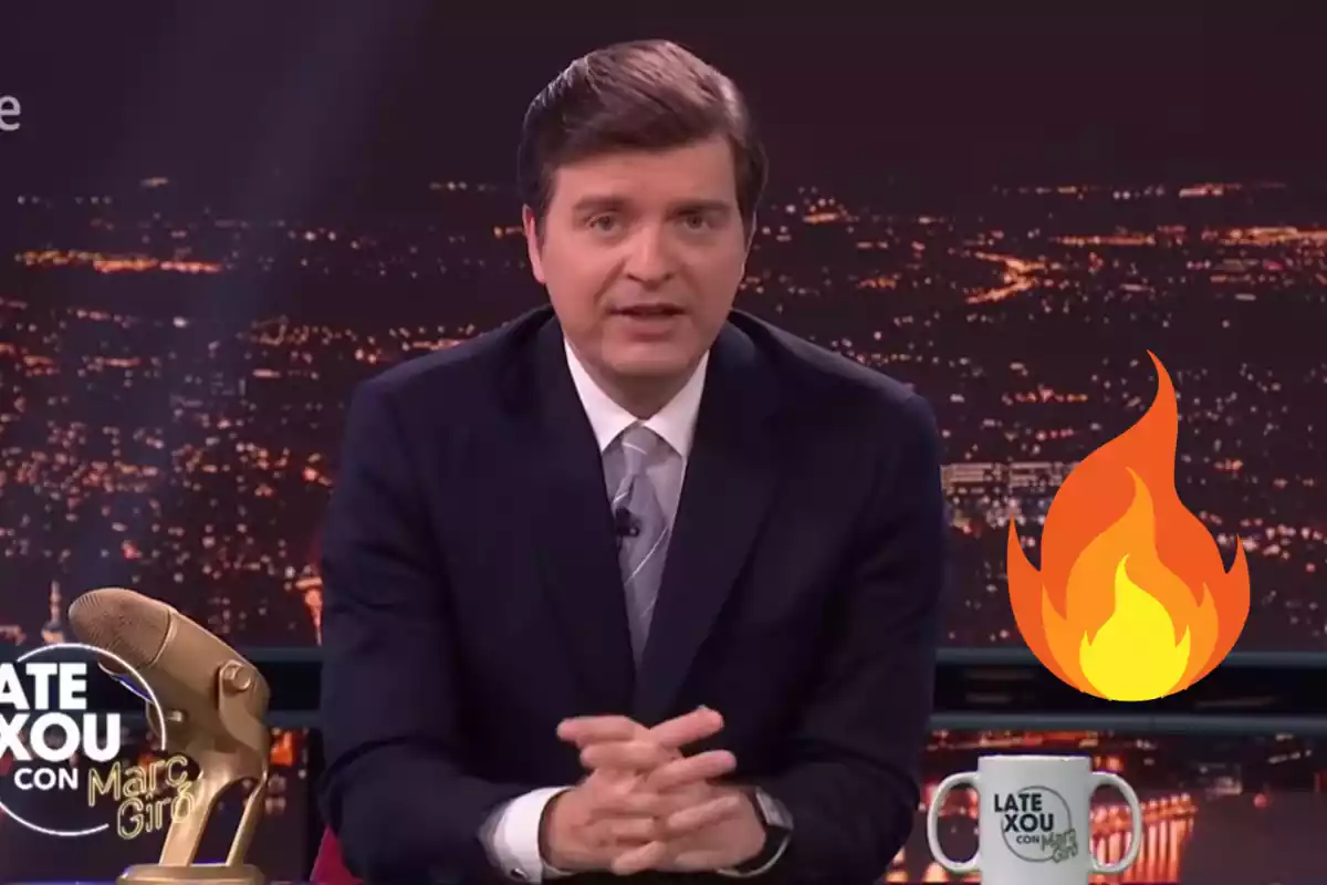 Muntatge amb una imatge de Marc Giró al seu programa "Late Xou amb Marc Giró" de RTVE. A la dreta una emoticona de foc.