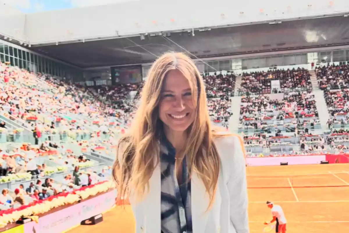 Una mujer sonriente en un estadio de tenis lleno de espectadores. Una mujer sonriente en un estadio de tenis lleno de espectadores.