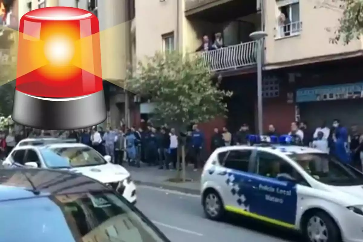 Una multitud se reúne en la calle mientras un coche de la policía local pasa con las luces encendidas y un ícono de sirena roja se superpone en la imagen.