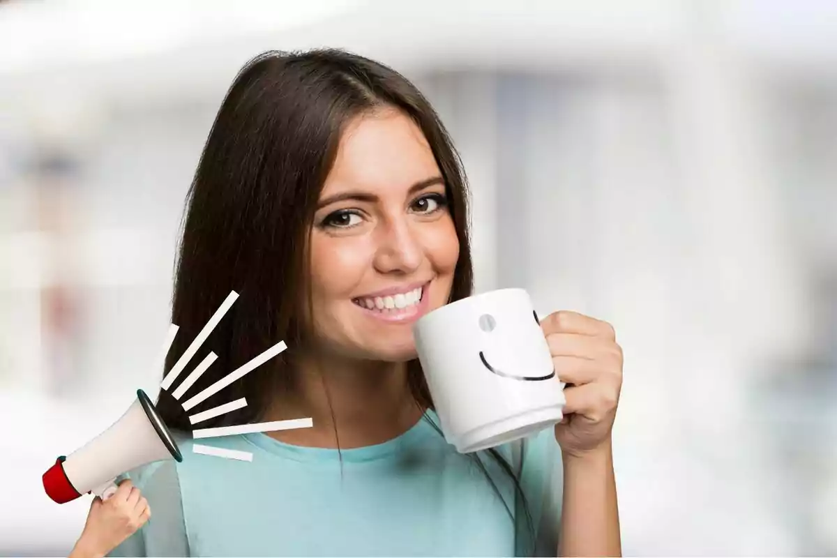 Una mujer sonriente sostiene una taza blanca con una cara feliz mientras un megáfono pequeño parece hablarle al oído.