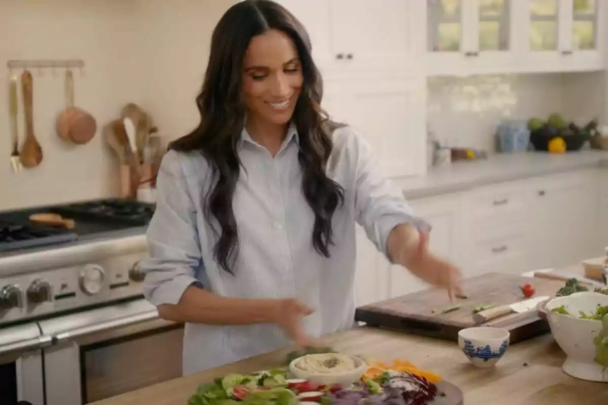 Meghan Markle smiles as she prepares a salad in a modern kitchen. Meghan Markle smiles as she prepares a salad in a modern kitchen.