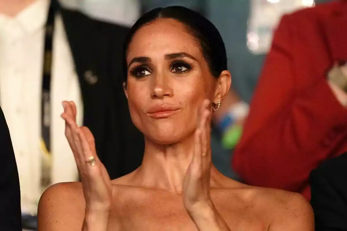 Meghan Markle clapping with a serious expression at an event. Meghan Markle clapping with a serious expression at an event.