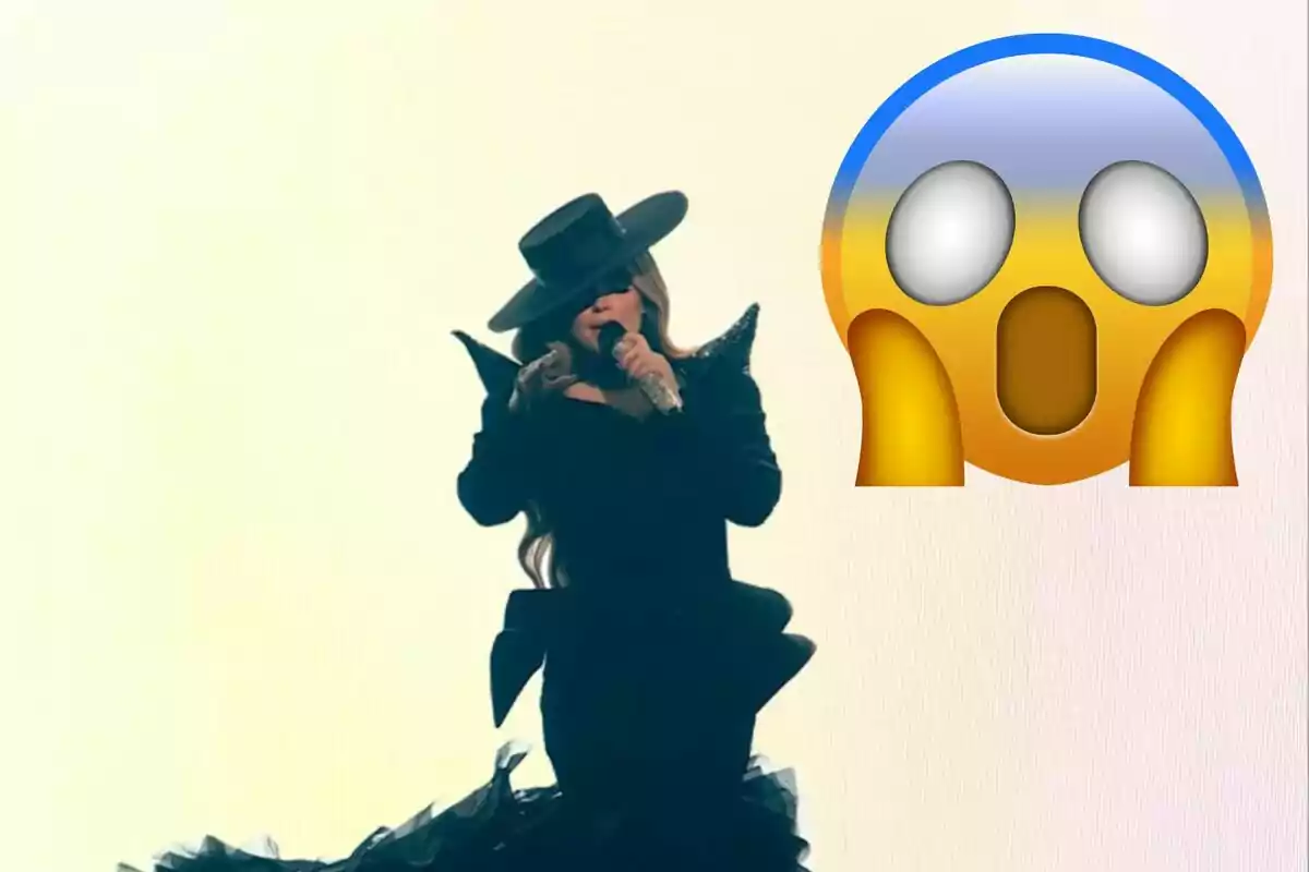 Una persona vestida de negre amb un barret gran canta en un escenari il·luminat mentre un emoji sorprès apareix al seu costat.