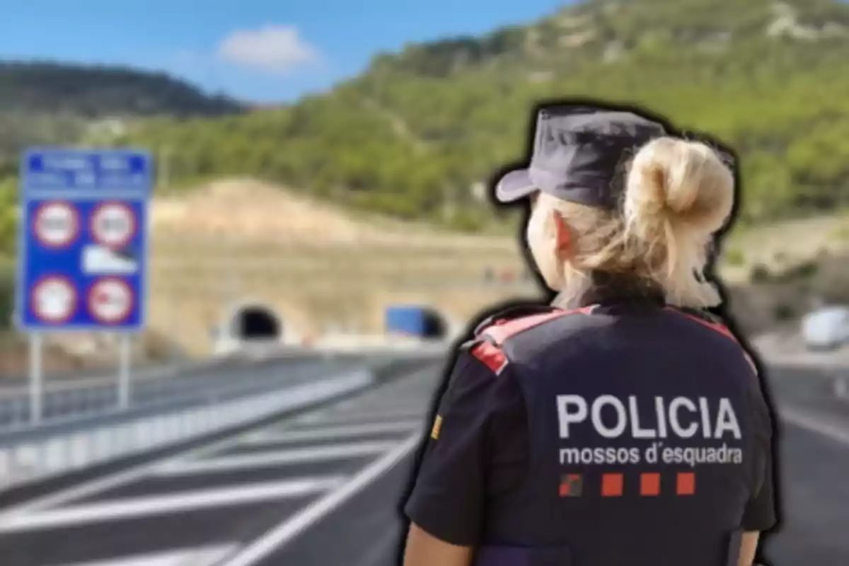 Una agent de policia d?esquena observa una carretera que condueix a un túnel en un entorn muntanyós.