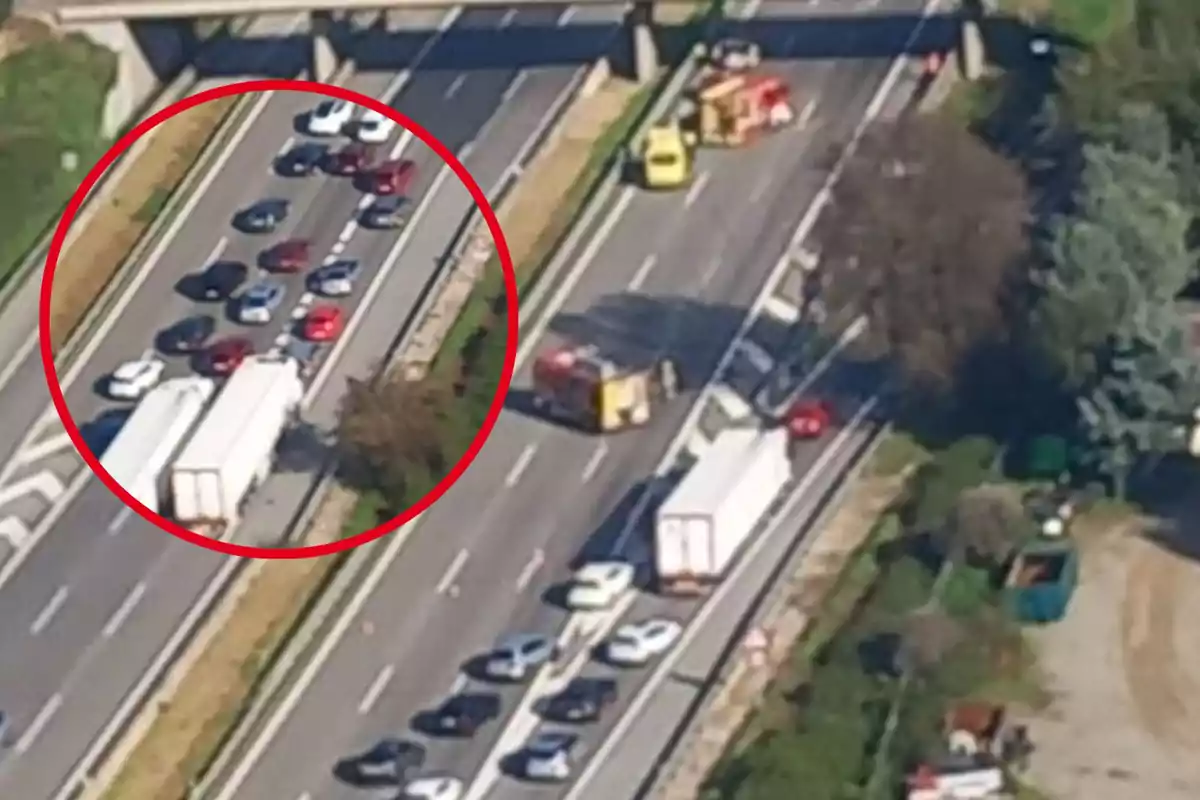 Imatge aèria d'una carretera amb trànsit detingut a causa d'un accident, on s'observen diversos vehicles i camions a la via, a més de la presència de serveis d'emergència.