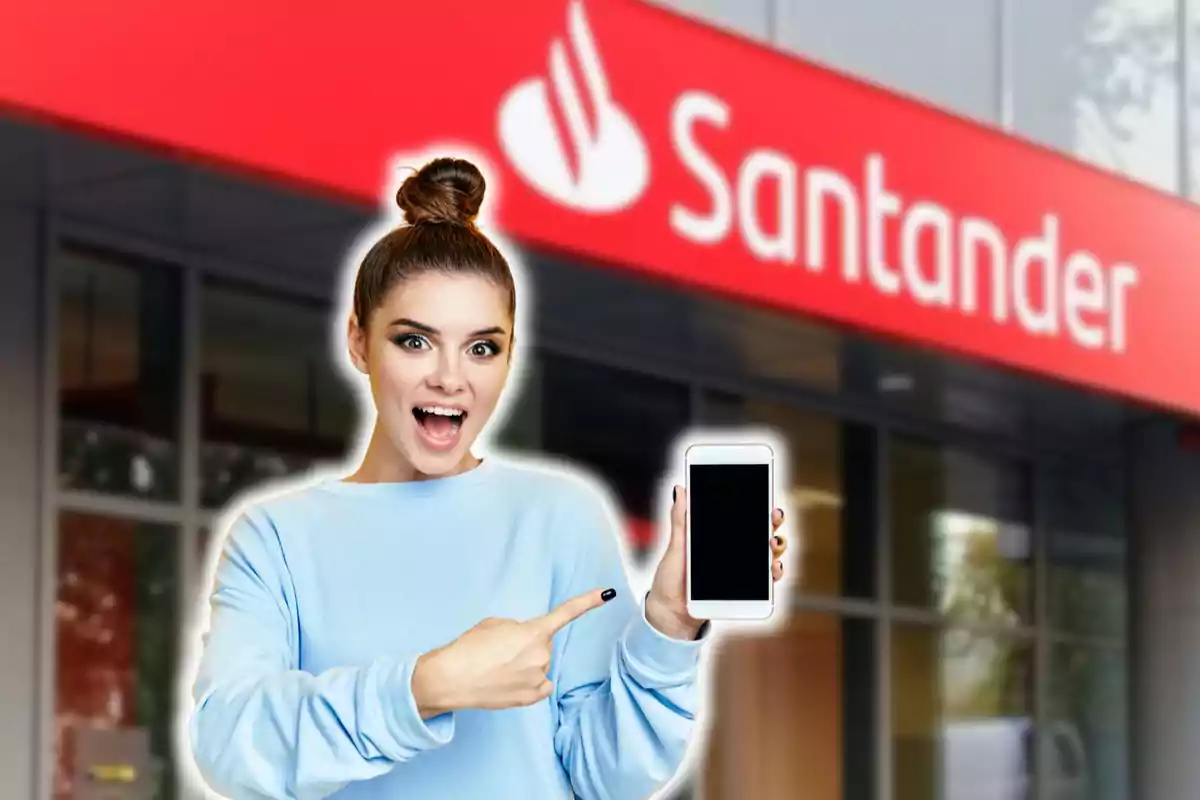 Una persona sonriente con un moño en el cabello sostiene un teléfono móvil frente a un edificio con el logotipo de Santander.