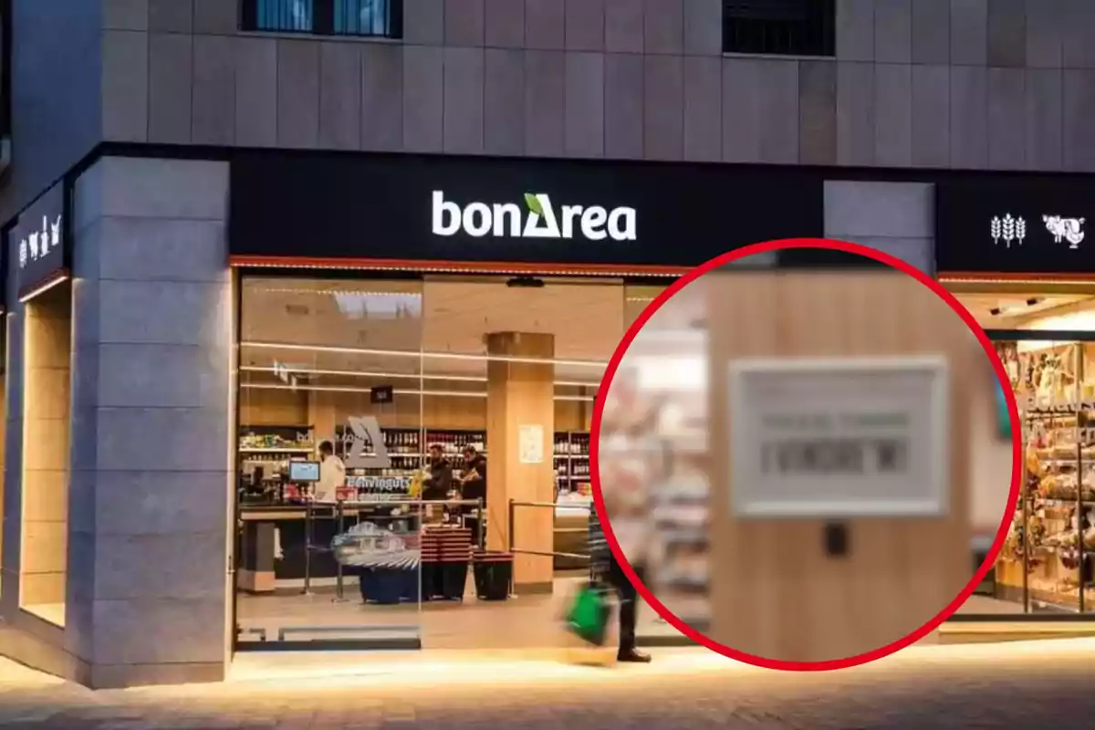 Una botiga bonÀrea amb façana il·luminada i un client sortint amb una bossa verda.