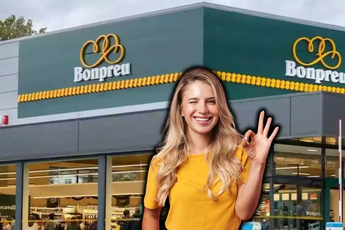 Una mujer sonriente con camiseta amarilla hace un gesto de aprobación frente a un supermercado Bonpreu.