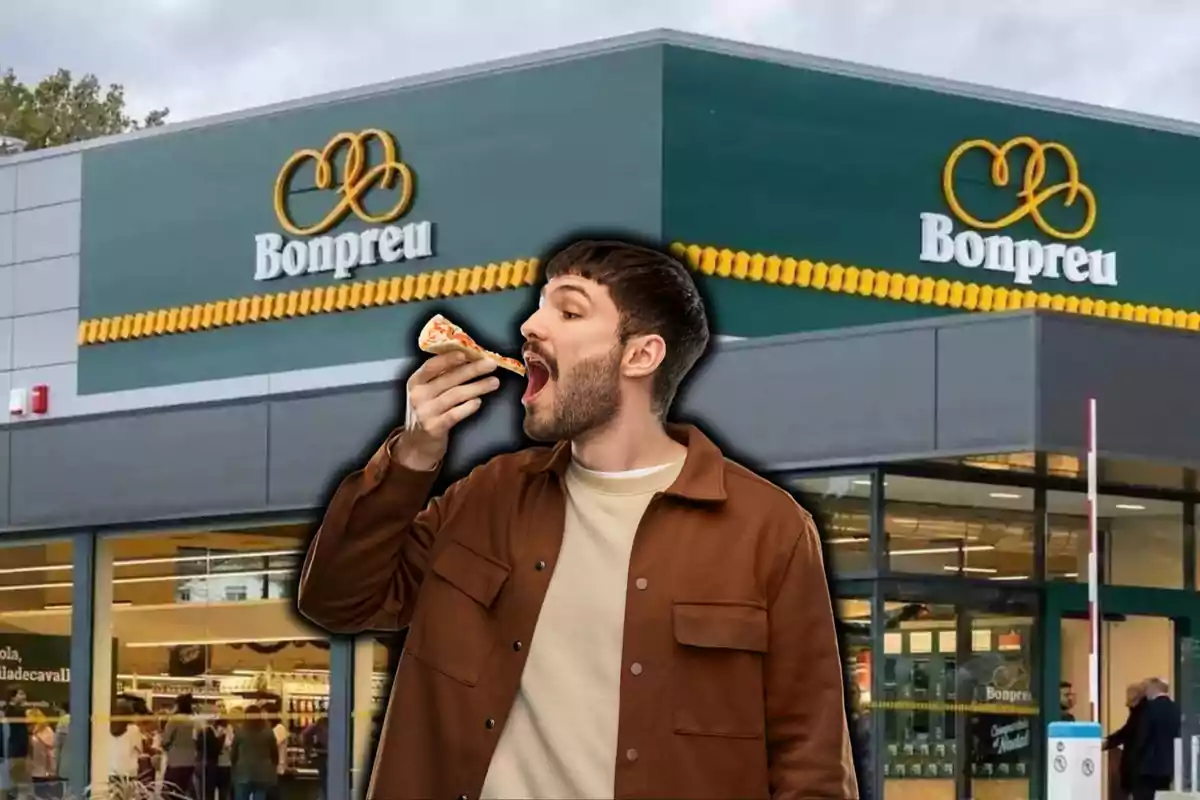 Un hombre comiendo una porción de pizza frente a un supermercado Bonpreu.