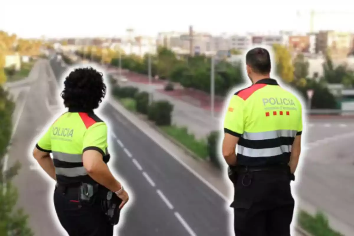 Dos agents de policia amb uniformes reflectors observen una carretera des d'un punt elevat.