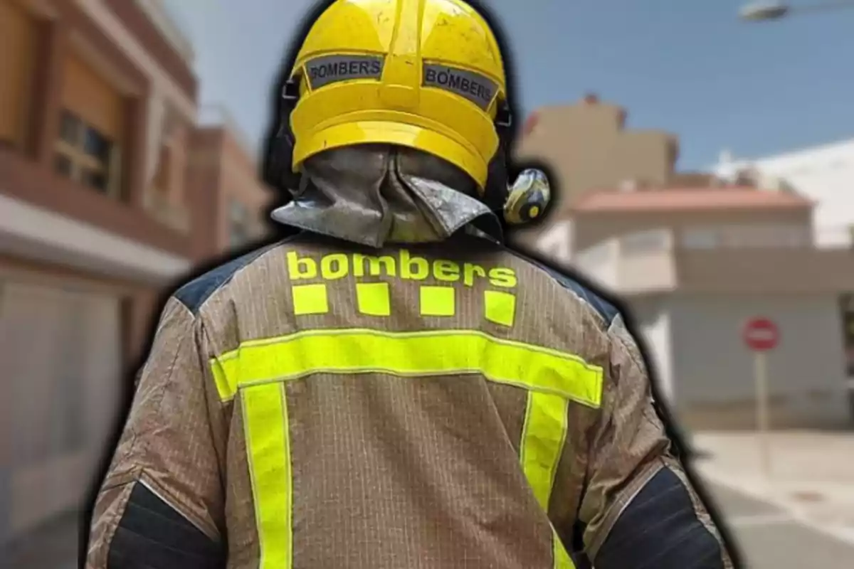 Bomber d´esquena amb uniforme i casc groc en un carrer urbà.