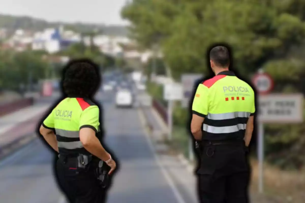 Dos agents de policia amb uniformes reflectors observen una carretera des d'un pont.