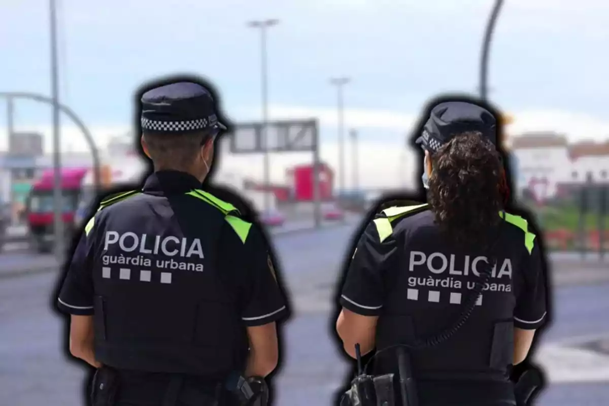 Dos agents de la guàrdia urbana d?esquena en un carrer urbà.