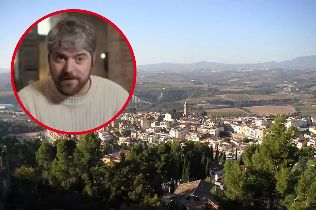 Un home amb cabell canós i barba en un requadre circular sobre un paisatge d´un poble envoltat de turons i vegetació.