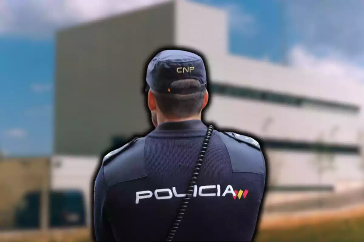 Un policia d?esquena amb uniforme del Cos Nacional de Policia davant d?un edifici modern.