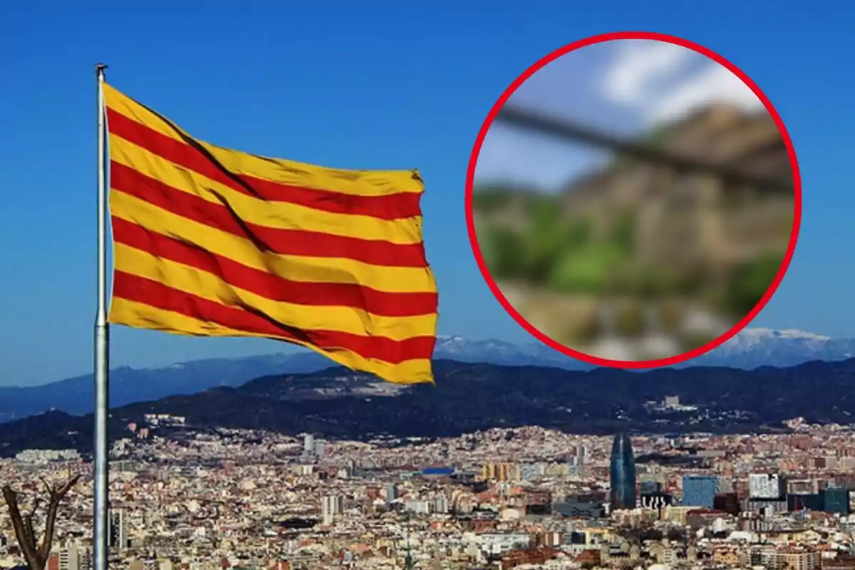 Bandera catalana ondeando sobre una ciudad con montañas al fondo y un círculo borroso en la esquina superior derecha.