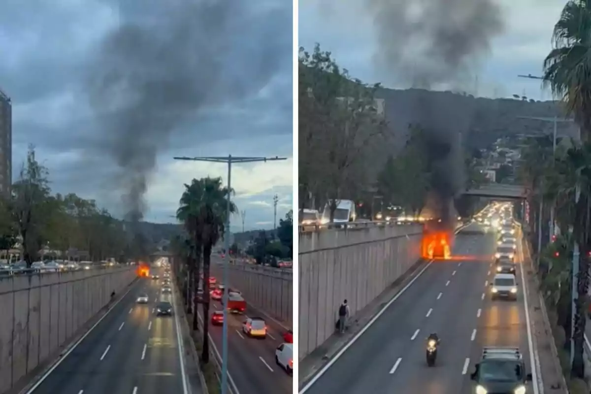 Un cotxe en flames en una carretera amb trànsit i fum negre elevant-se al cel.