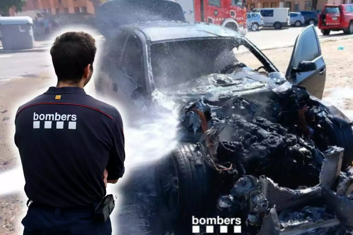 Un bombero apaga un incendio en un coche quemado con una manguera de agua.