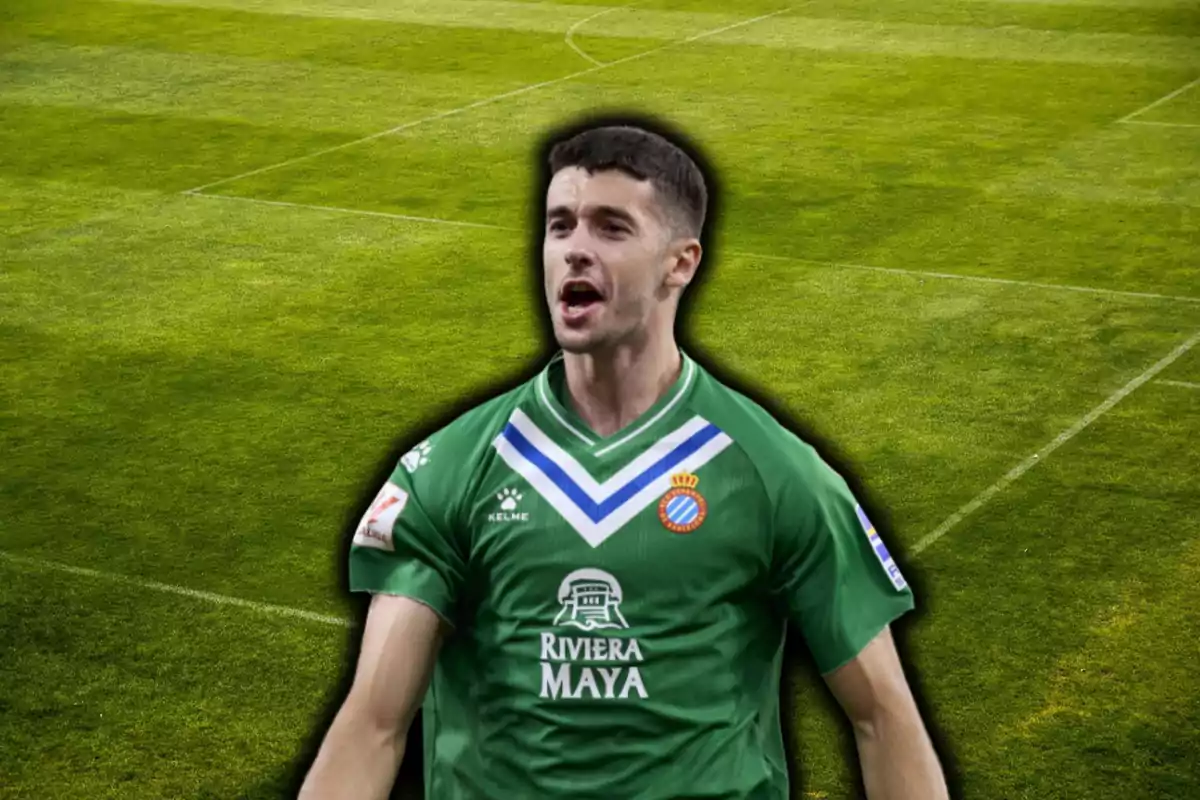 Jugador de fútbol con uniforme verde del Espanyol celebrando en un campo de fútbol.