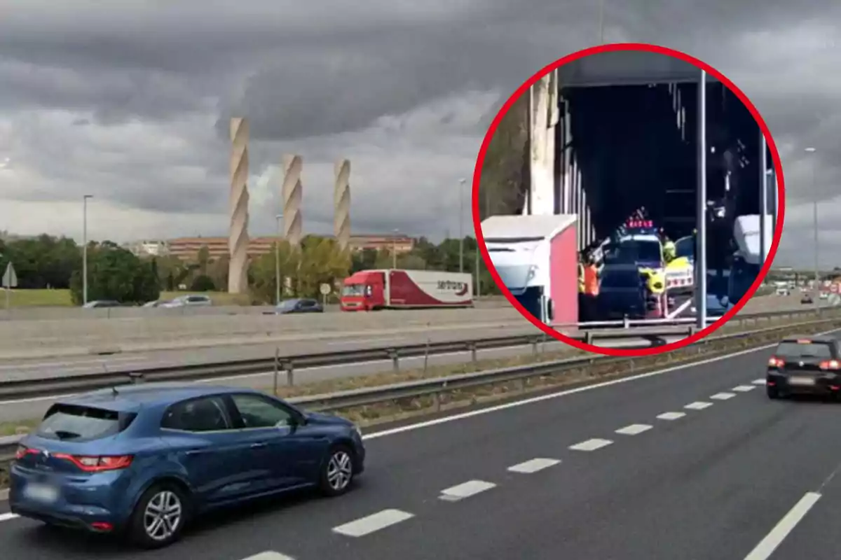 Una carretera amb diversos vehicles circulant i un camió vermell al carril central, al fons es veuen tres estructures altes i recargolades, el cel està ennuvolat i hi ha un cercle vermell que destaca un accident en un túnel.