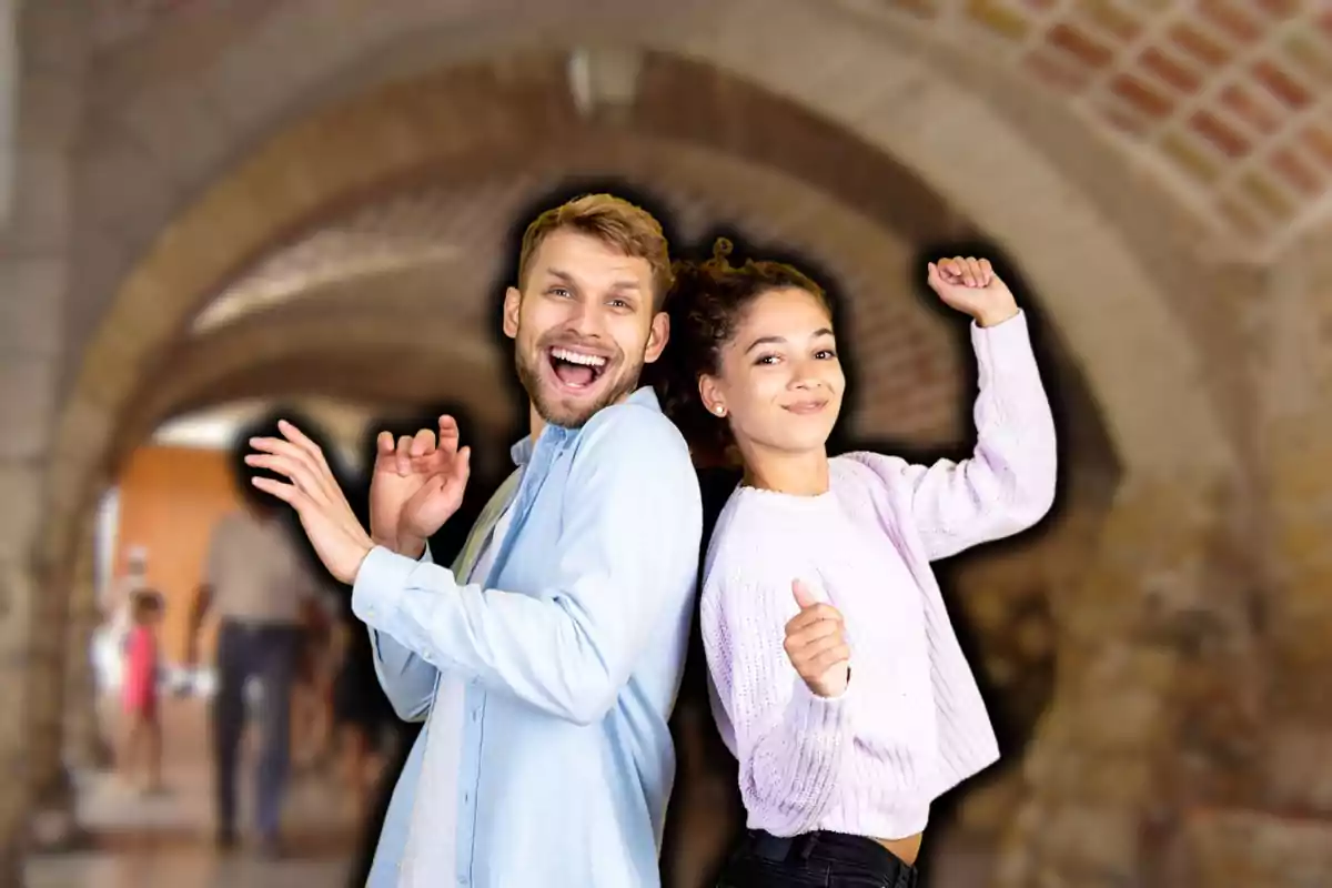 Dos personas sonrientes bailando en un pasillo con arcos de ladrillo.