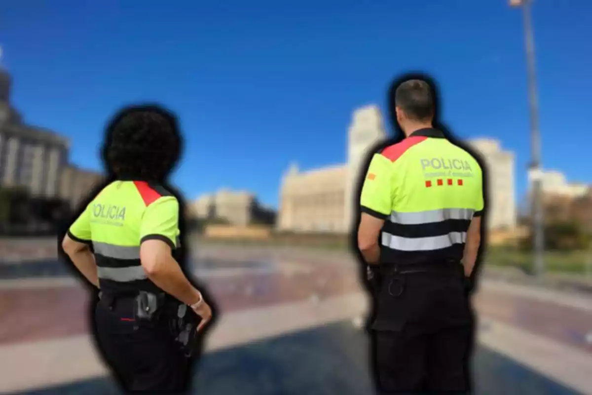 Dos agents de policia amb uniformes d?alta visibilitat d?esquena en un entorn urbà.