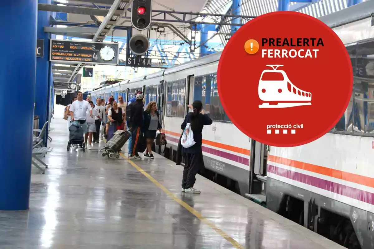 Persones en una andana de tren amb un cartell de prealerta Ferrocat de protecció civil.