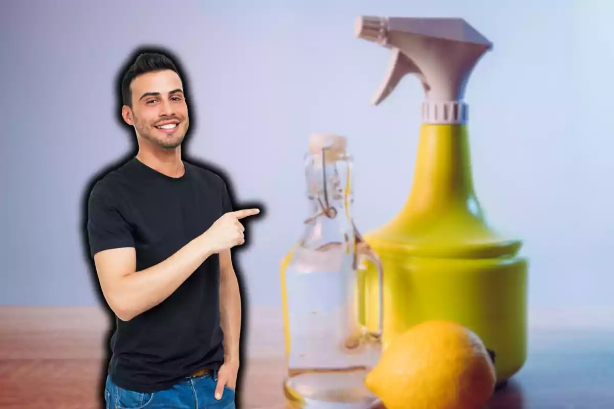 Un hombre sonriente señala hacia una botella de vidrio, un atomizador amarillo y un limón sobre una mesa.