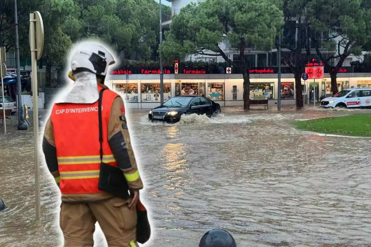 Un bomber observa un carrer inundat mentre un cotxe negre intenta travessar l?aigua.