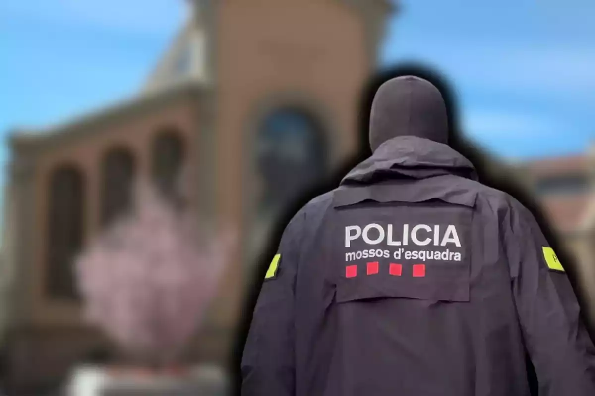 Un agente de los Mossos d'Esquadra de espaldas con un edificio borroso de fondo.