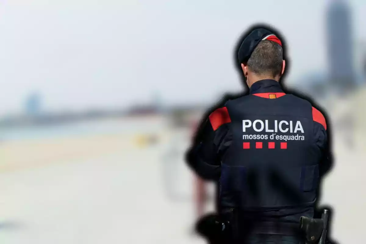 Un agent dels Mossos d'Esquadra d'esquena a una platja.