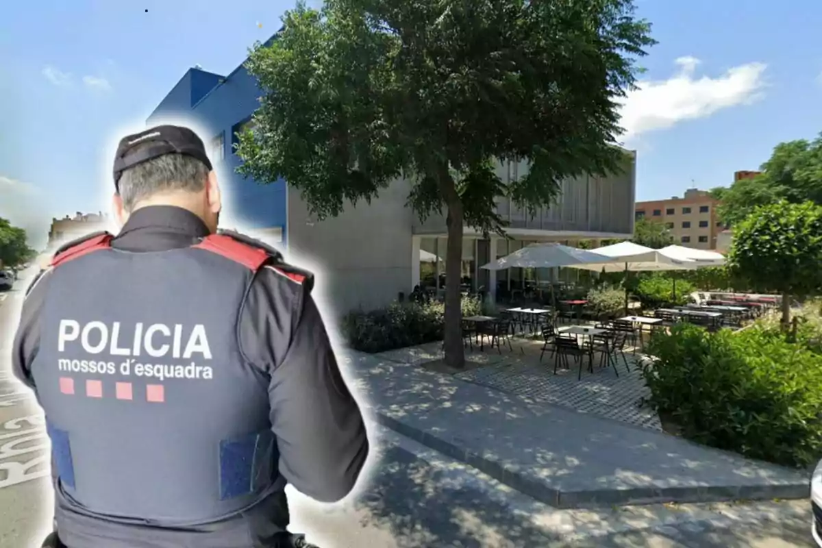 Un agent dels Mossos d'Esquadra d'esquena davant d'un edifici amb una terrassa exterior.