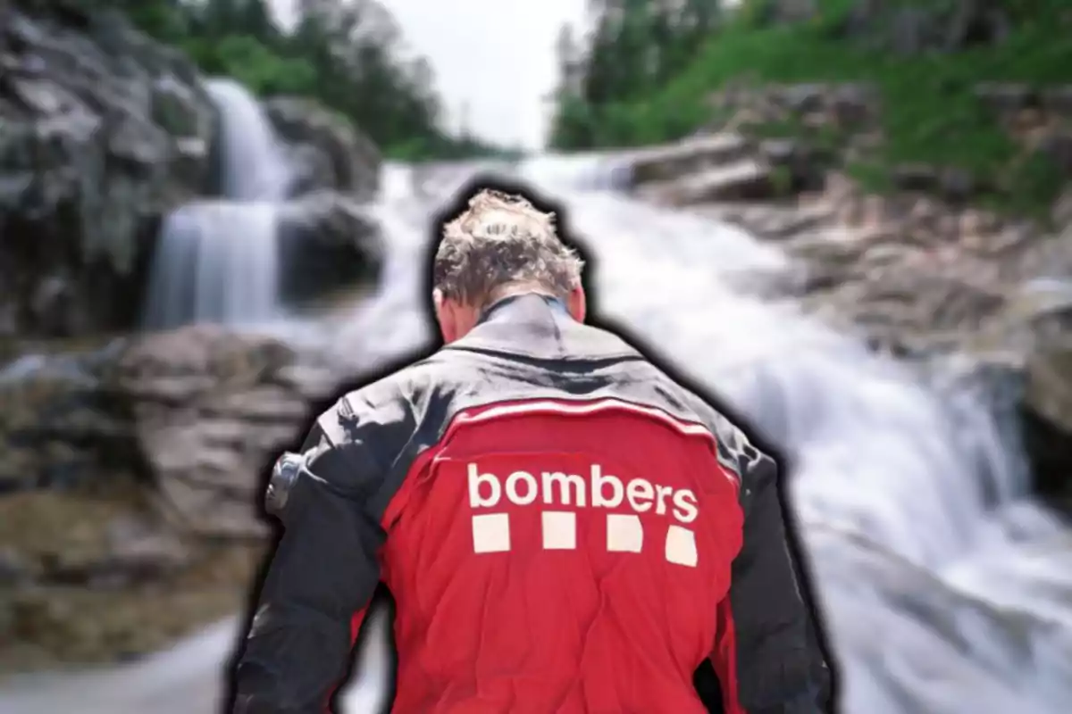 Persona de espaldas con chaqueta roja que dice "bombers" frente a una cascada.