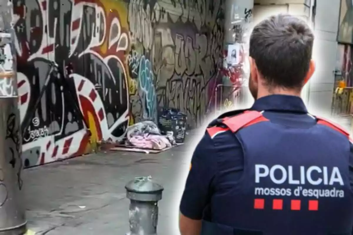 Un agent de policia d?esquena observa un carrer amb grafits i una persona dormint a terra.