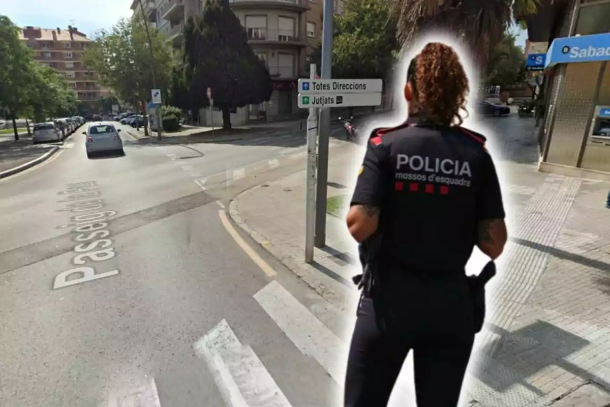 Una agent de policia dels Mossos d'Esquadra d'esquena a un carrer de la ciutat, amb un cartell d'adreces i un banc al fons.