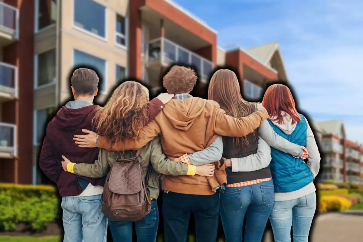 Un grupo de cinco personas de espaldas abrazándose frente a un edificio moderno.