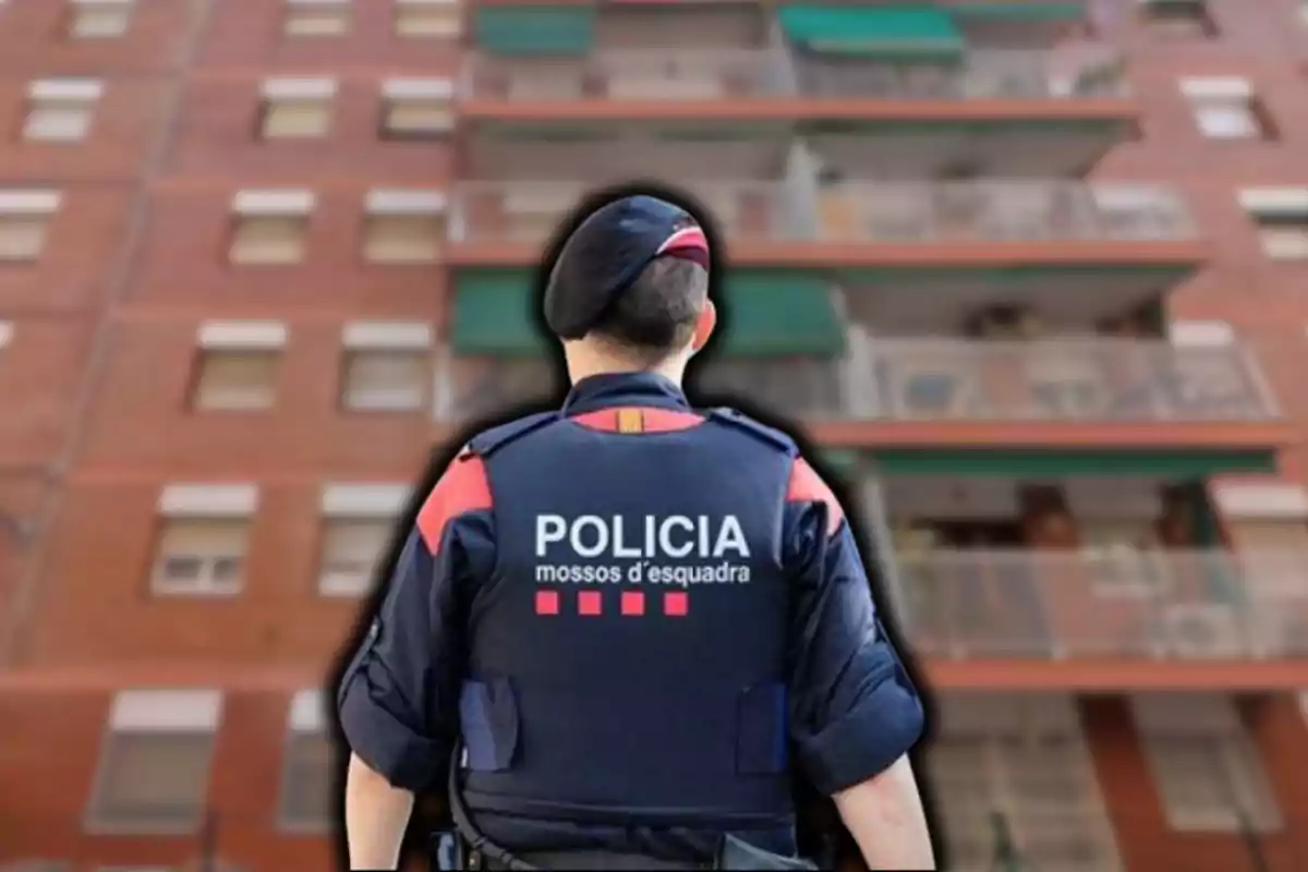 Un agent de policia d?esquena davant d?un edifici d?apartaments.