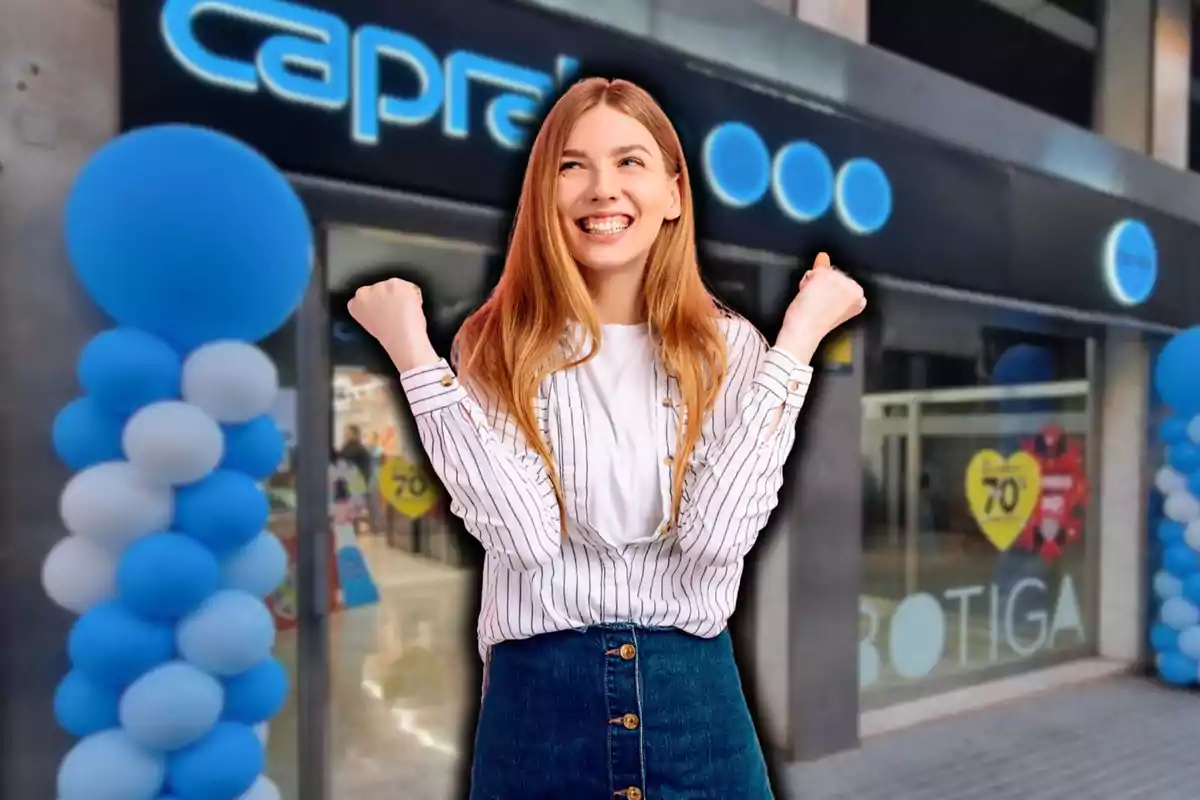 Una mujer sonriente con los puños levantados frente a una tienda decorada con globos azules y blancos.