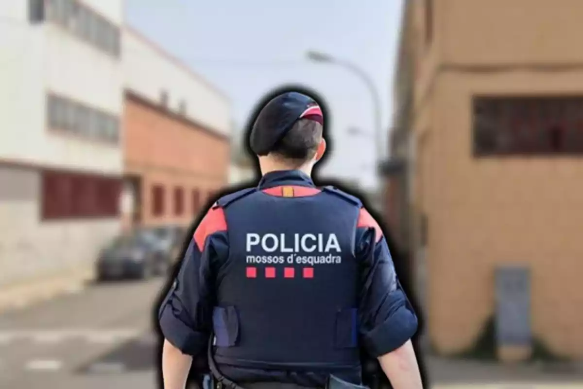 Un agente de policía de los Mossos d'Esquadra de espaldas en una calle urbana.