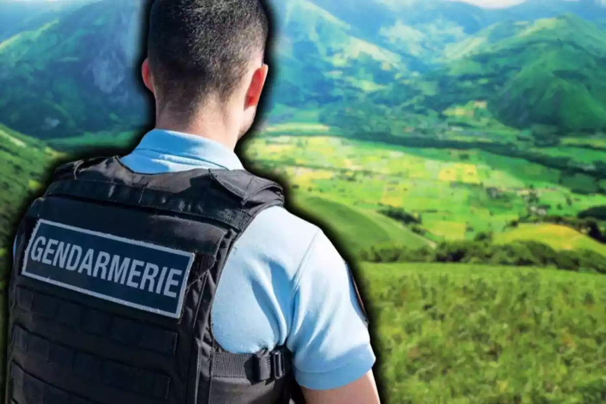 Un gendarme de espaldas observa un paisaje montañoso verde.