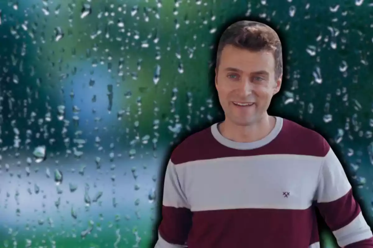 Un hombre sonriente con un suéter a rayas frente a un fondo de gotas de lluvia en una ventana.