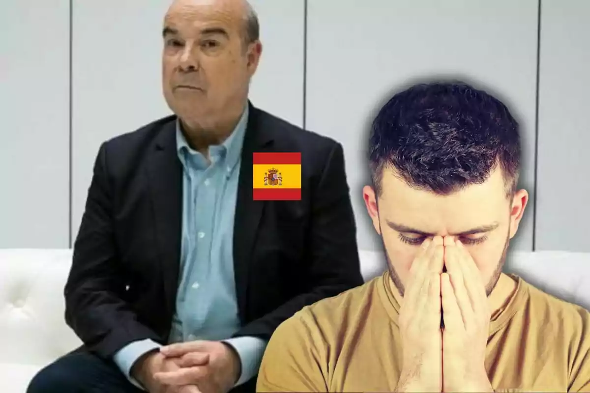 Un hombre mayor con traje y una bandera de España en su chaqueta está sentado junto a un joven que se cubre el rostro con las manos en un gesto de preocupación.