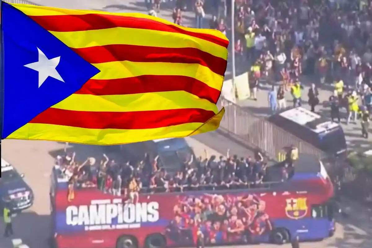 Un autobús descapotable ple de persones celebrant mentre una bandera oneja en primer pla.