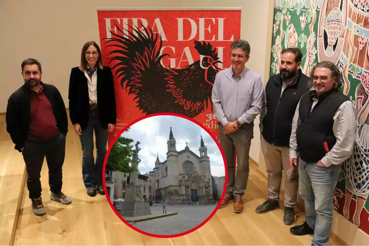 Un grup de persones posant davant d´un cartell de la Fira del Gall amb una imatge circular d´una església al centre.